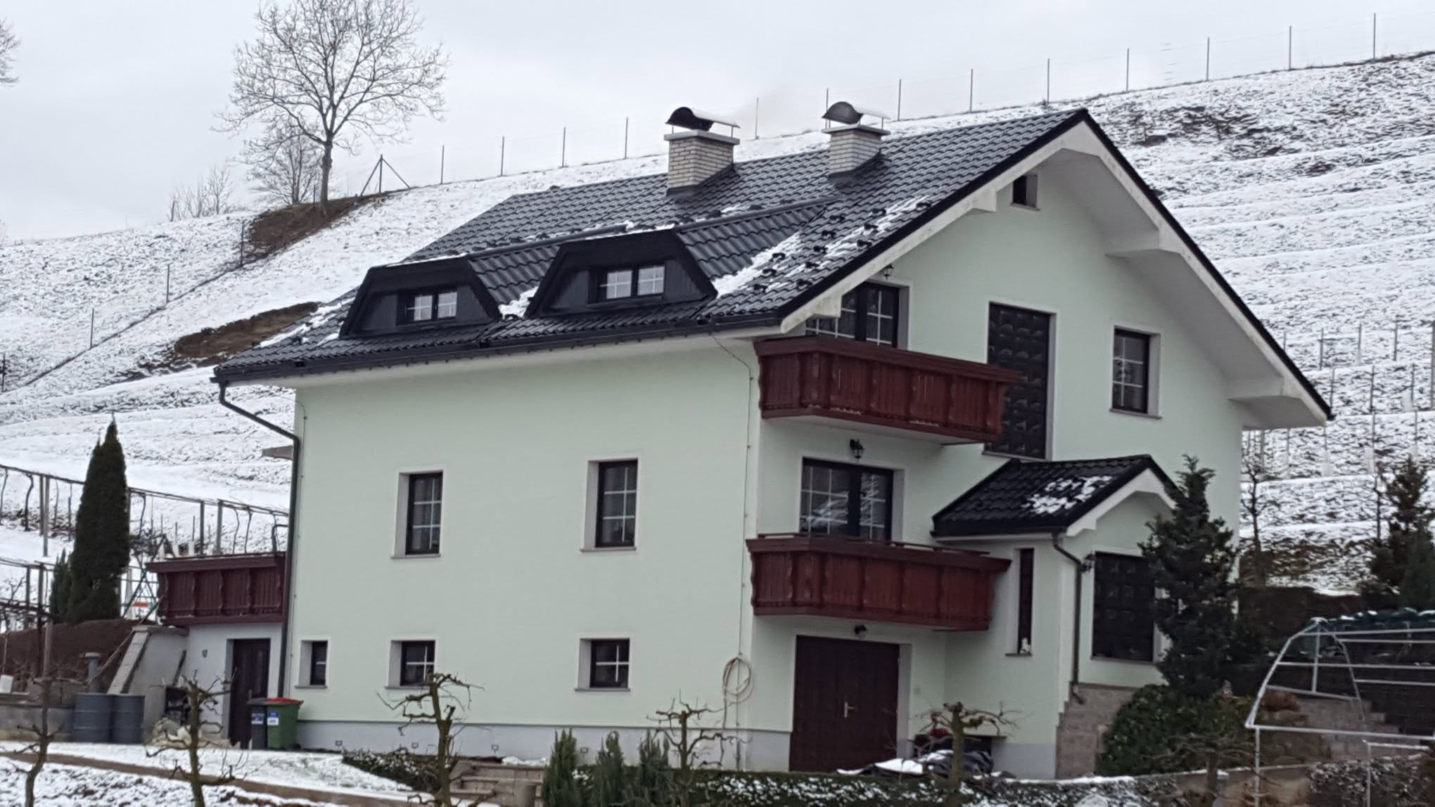 Temna kovinska kritina z dvema frčadama na enodružinski hiši pozimi