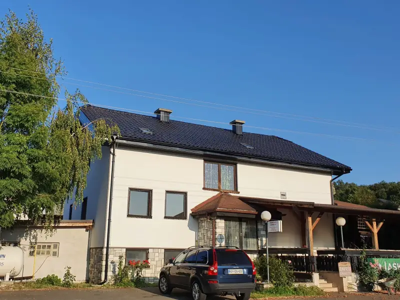 Temna kovinska kritina s strešnimi okni na dvonadstropni stanovanjski in poslovni hiši
