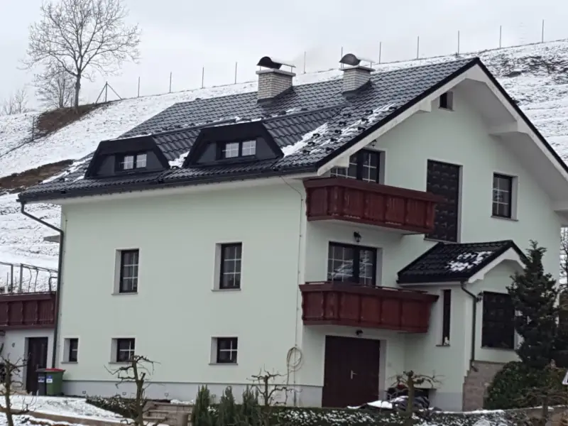 Temna kovinska kritina z dvema frčadama na enodružinski hiši pozimi
